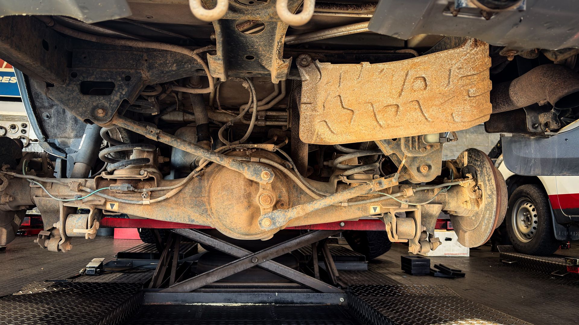 Detailed view of a car's rusty suspension system during repair in a garage.